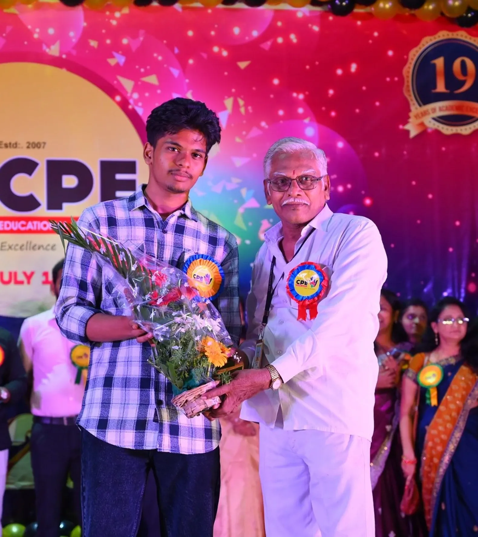 A student presenting a bouquet to a guest on the Annual Day stage