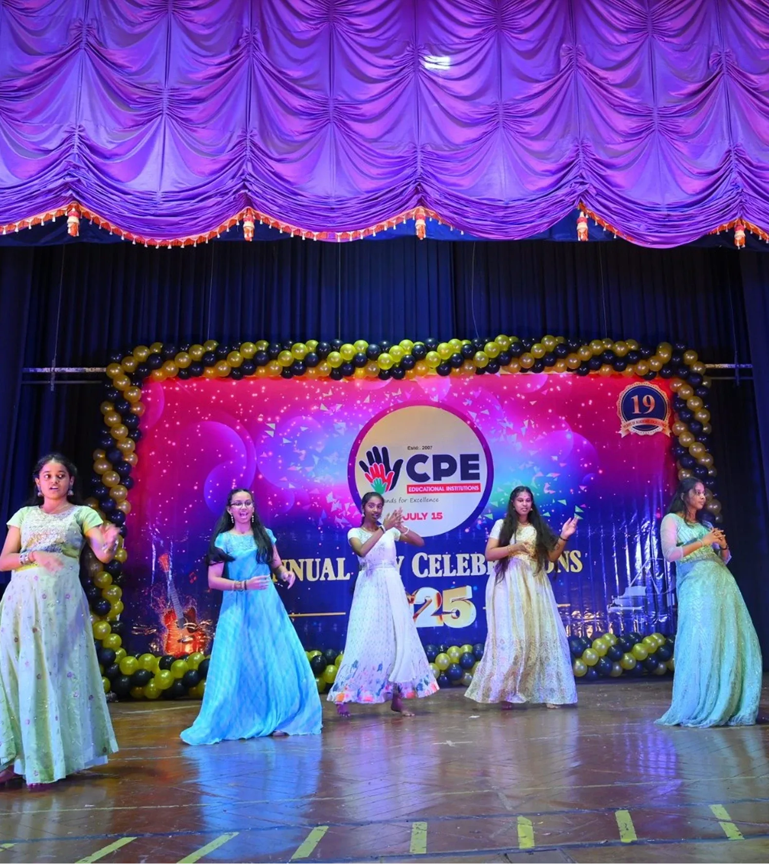 Students in colourful gowns performing together on the Annual Day stage